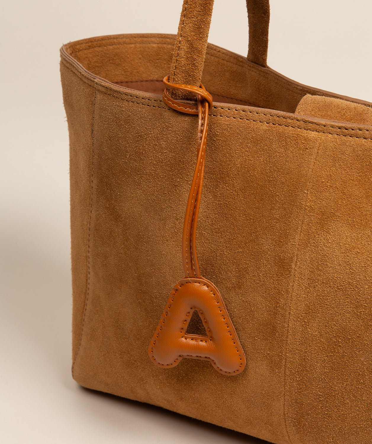 tan leather charm close-up showing embossed lettering detail