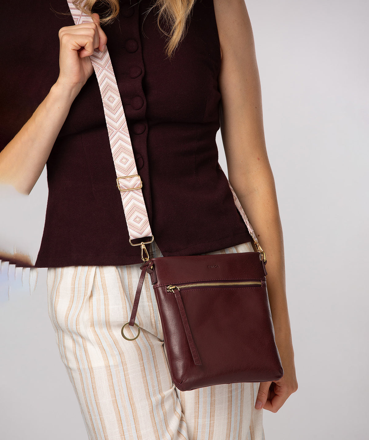 Bag strap detail showing adjustable gold hardware and geometric pattern